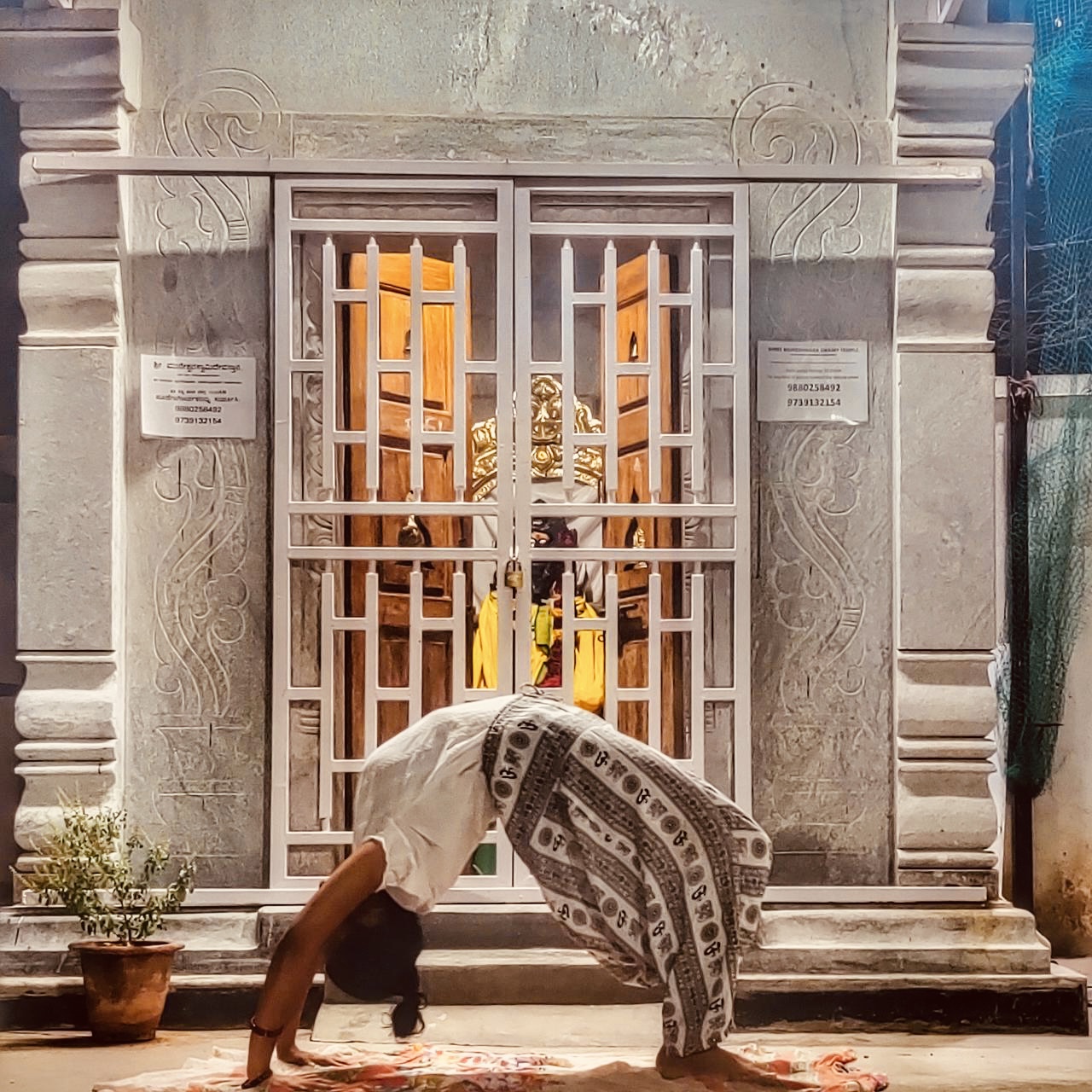 Swathi practicing the chakrasana in front of a mandir
