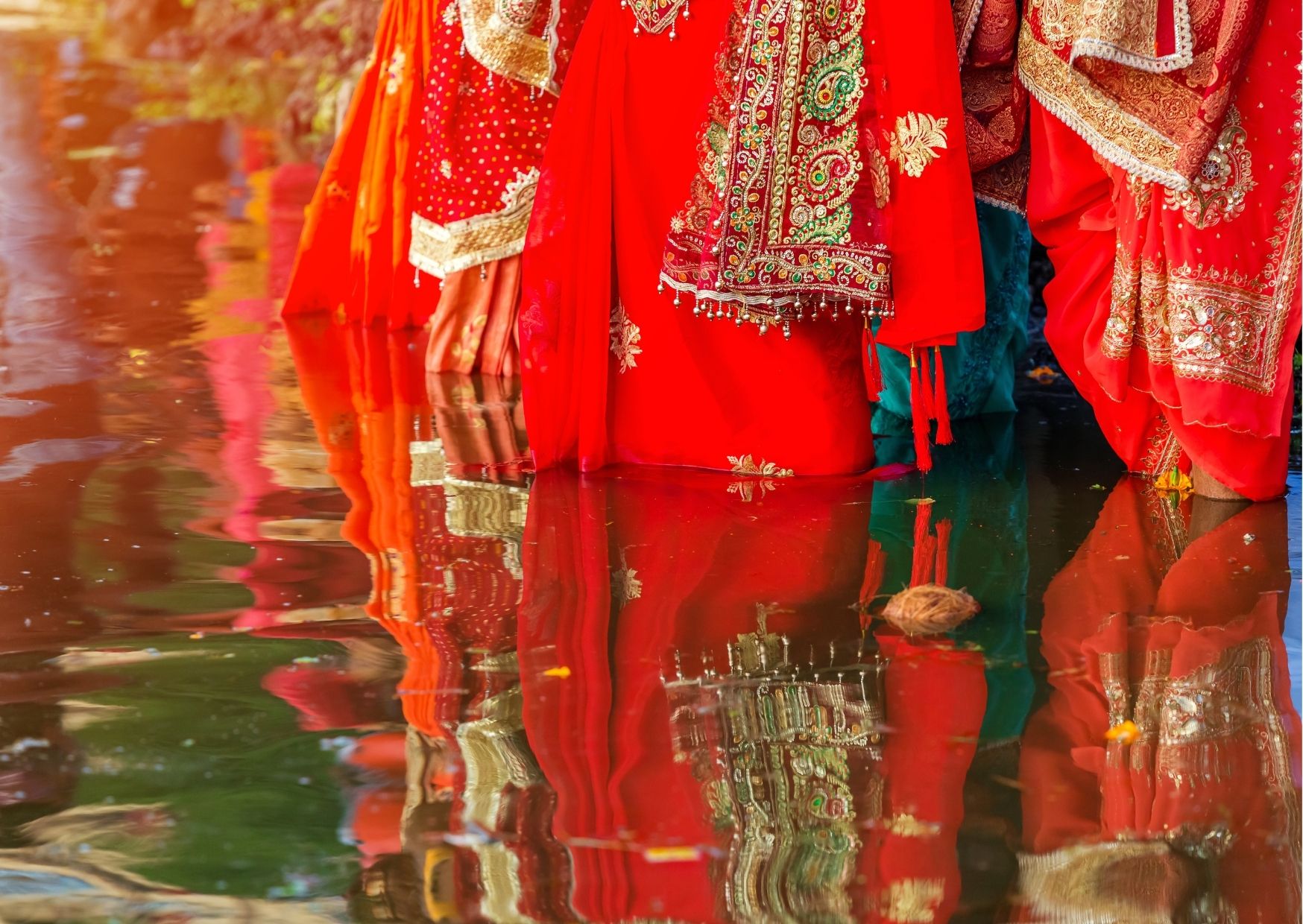 ladies in auspicious red sarees performing chhath puja
