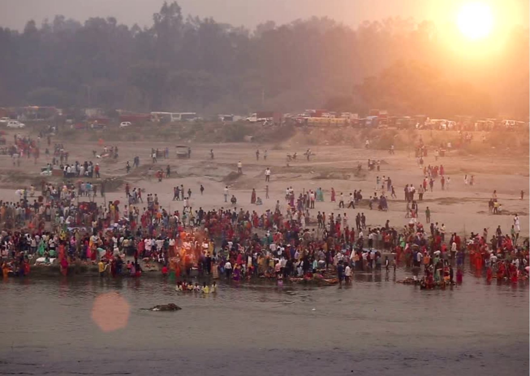 hundreds of people on a beach worshipping Sun God for Chhath Puja at sunset