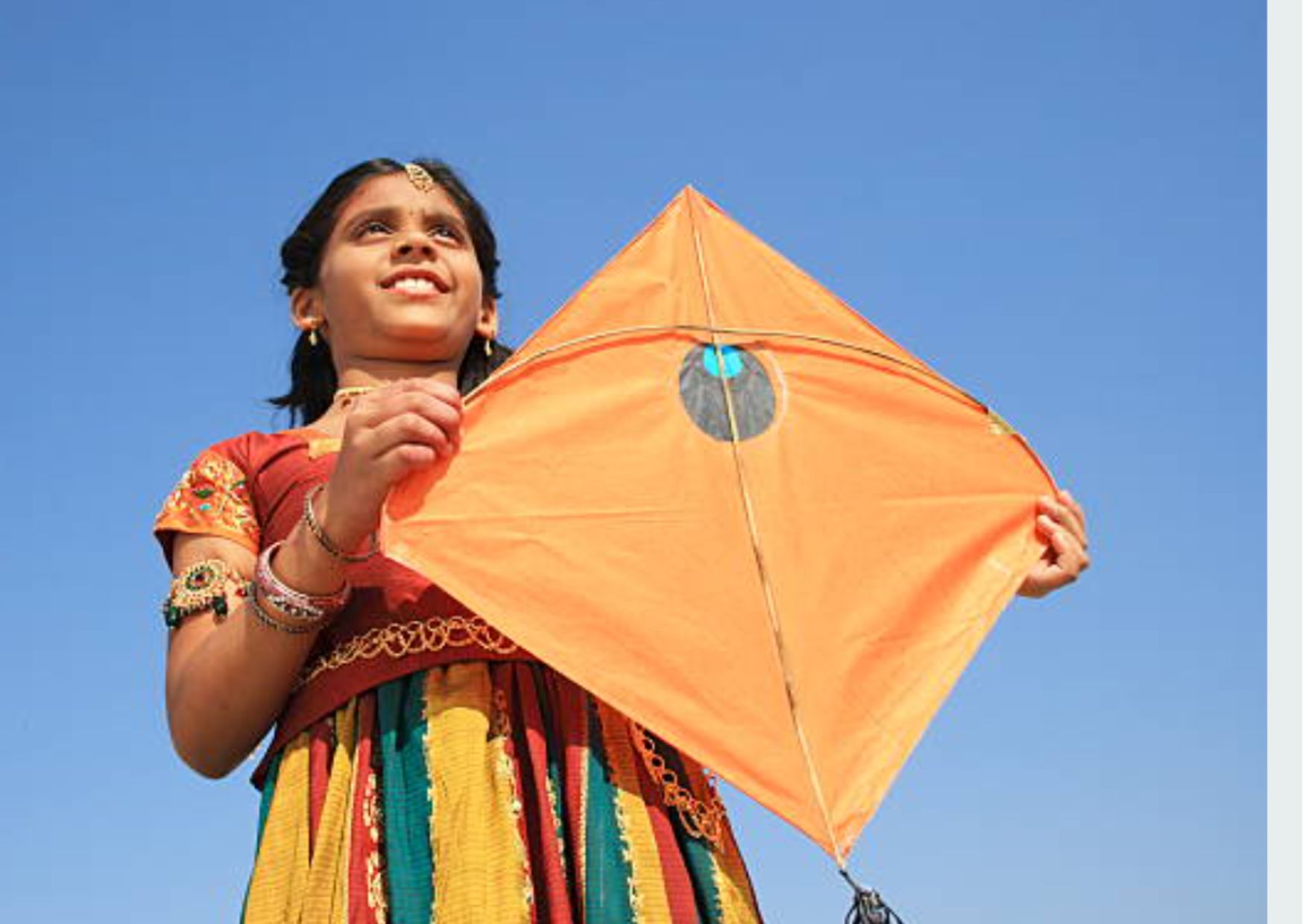 A young girl holding a kite and observing the sky for Uttrayan, the kite festival of Gujarat